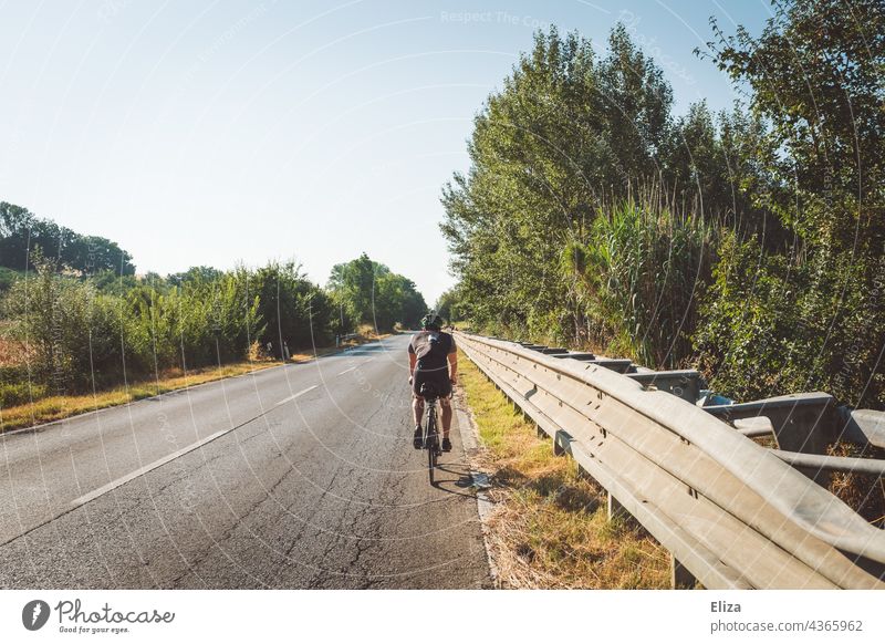 Racing cyclist in sportswear rides his bike on an Italian country road Racing cycle Road cyclist Sportswear Country road Italy Mediterranean Summer vacation