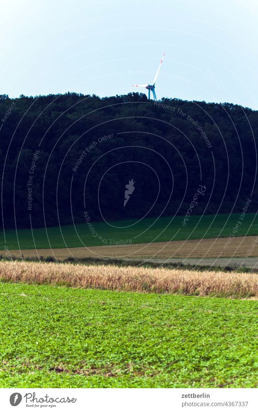 Wind turbine behind the forest Pinwheel wind power Wind energy plant Renewable energy Forest Edge of the forest Agriculture acre Field rain Feldrain Hill Sky