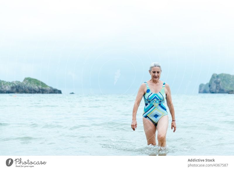 Happy senior woman bathing in ocean beach sea happy water active swimsuit fit summer female positive old aged gray hair healthy lifestyle enjoy swimwear