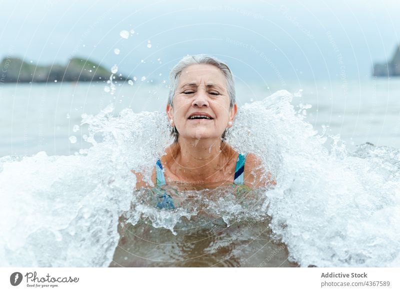 Old woman swimming in sea water senior beach active summer ocean healthy lifestyle female old aged gray hair enjoy bath practice nature summertime recreation