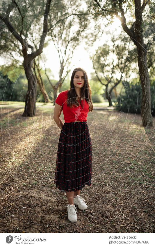 Stylish woman standing on meadow in park summer garden lawn style trendy enjoy peaceful sunlight female lifestyle nature carefree calm charming outfit serene