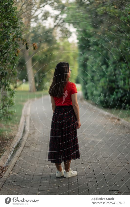 Stylish woman standing on meadow in park summer garden lawn style trendy enjoy peaceful sunlight female lifestyle nature carefree calm charming outfit serene