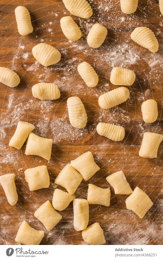 Raw gnocchi on wooden table raw pasta cook row kitchen home lunch food meal prepare dish cuisine portion culinary italian tradition authentic fresh lumber