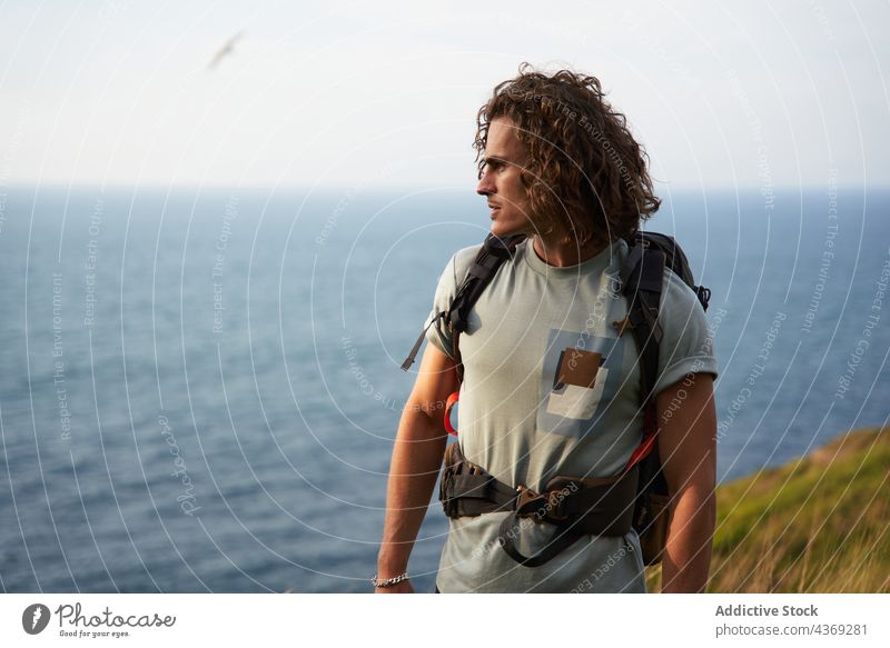 Traveling man walking on hill against sea travel backpacker field summer trekking traveler freedom male meadow hike nature adventure countryside vacation