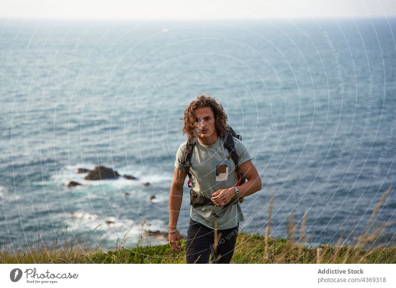 Traveling man walking on hill against sea travel backpacker field summer trekking traveler freedom male meadow hike nature adventure countryside vacation