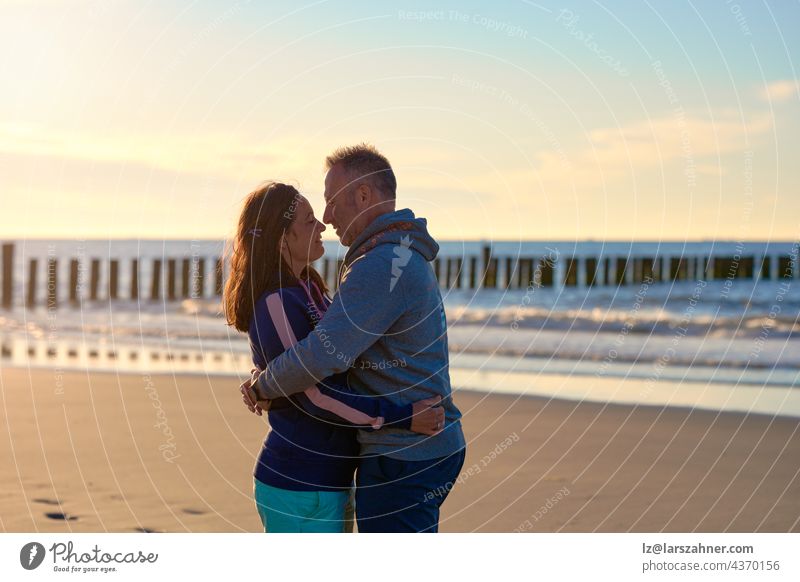 Romantic middle-aged couple hugging on a tropical beach at sunset looking lovingly into each others eyes with lateral copyspace woman romantic sea ocean