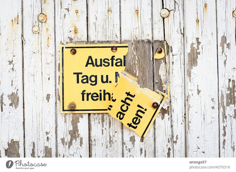 Broken yellow sign "Keep exit clear day and night" still hanging on garage door shattered Signs and labeling Old Signage Exterior shot Colour photo Deserted