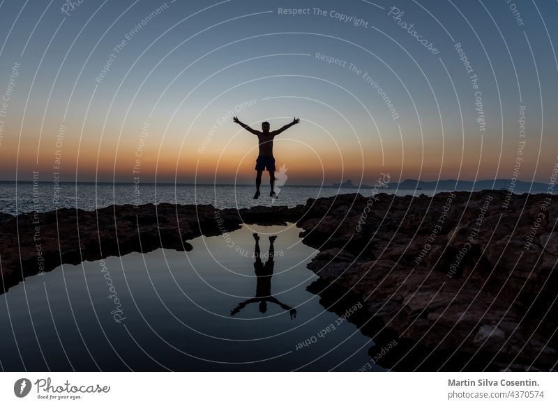 Young man jump the Sunset in Can Marroig in Formentera, Spain adult animal background balearic islands balearics beach beautiful beauty blue boat clouds coast