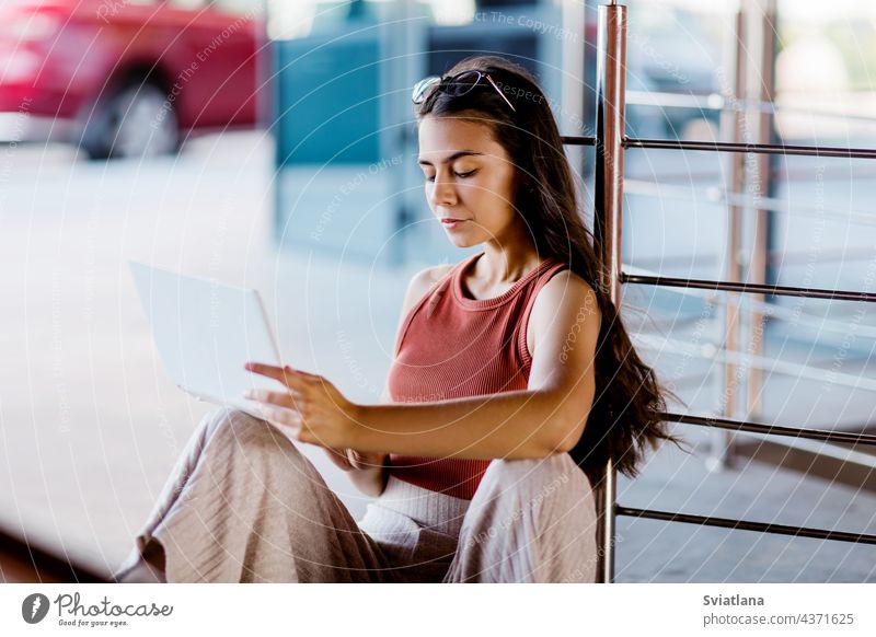 Portrait of a student girl sitting on a city staircase and using a laptop outdoors stairs education reading campus college woman young computer happy portrait