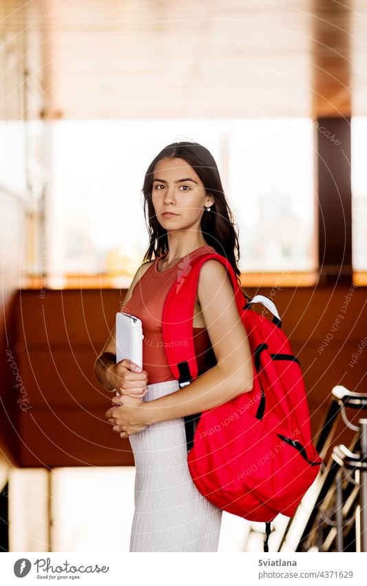 Portrait of a charming student girl with a backpack and a laptop stairs holding smiling joyful college people staircase school walking woman young education