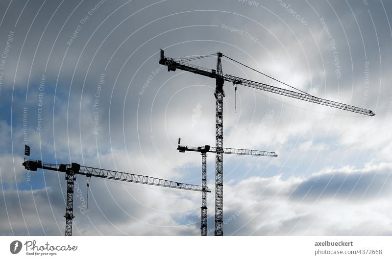 Cranes silhouetted against cloudy sky Construction crane Construction site Sky Clouds Silhouette construction industry Industry construction sector Dark clouds