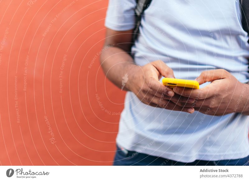 African man with smart phone next to a red wall confident male adult african american black ethnicity outdoors technology music happiness attitude enjoyment