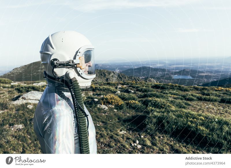 Confident spaceman standing in countryside confident mission brave concept highland explore science spacesuit male astronaut helmet adventure protect cosmonaut