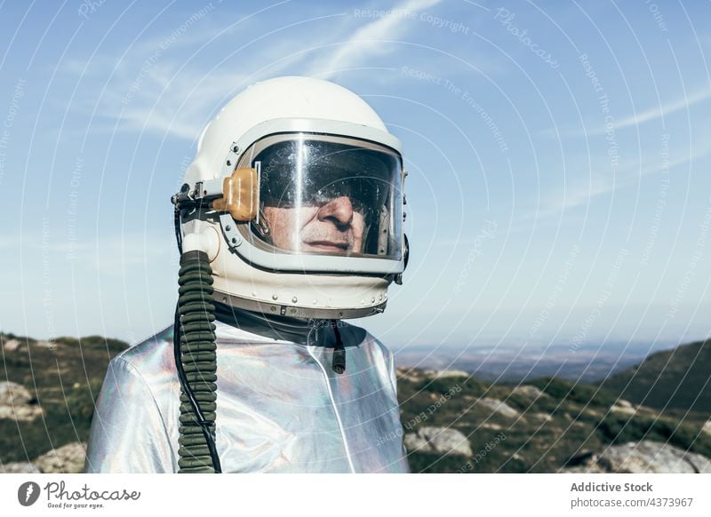 Confident spaceman standing in countryside confident mission brave concept highland explore science spacesuit male astronaut helmet adventure protect cosmonaut