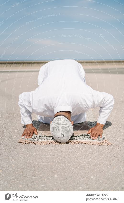 Islamic man praying on mat on beach muslim arab islam religion kneel bow tradition culture rug ritual worship holy male ethnic ground bend authentic sand arid