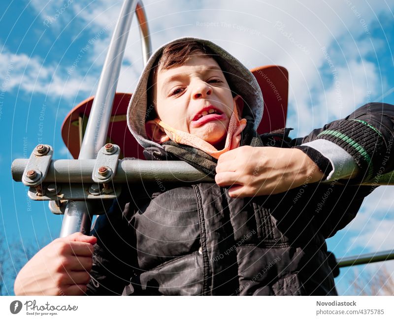 Young boy doing a funny face gesture young child isolated outdoors outside alone single male caucasian mask expression expressive ugly disgusting nasty