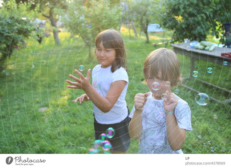 children having a great time playing with soap ballons pursuit of happiness pursuit - concept positive emotion Playful people multi colored baloons