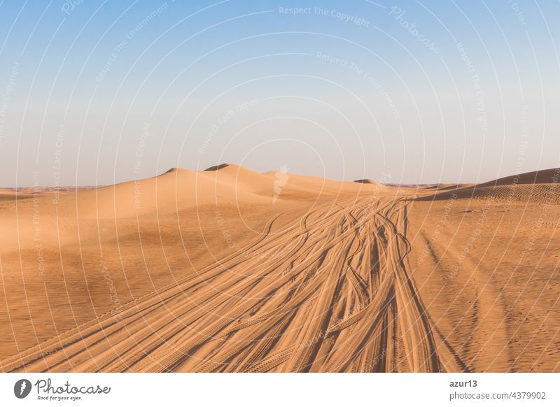 Lonely desert road driving lanes amid golden sand dunes. Climate change heat and dryness up to horizon produces erosion and desertification. Landscape showing waste adventure travel tourism