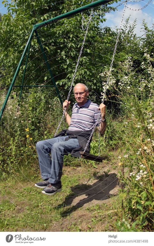 the child in the man - senior swings in the sunshine in a flower garden Human being Man Senior citizen 70+ Swing To swing Garden Light Shadow Joy fun