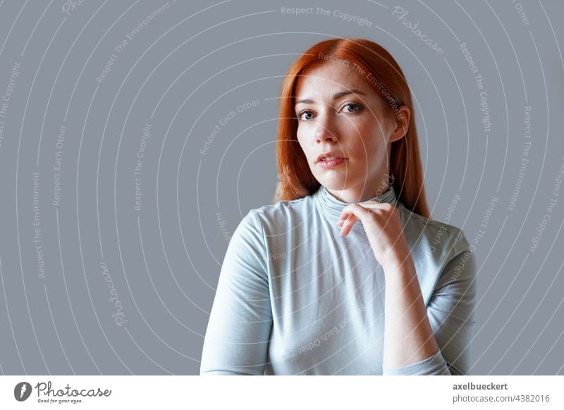 contemplative young woman with long red hair and light blue turtleneck think pensive thoughtful serene girl portrait lady model person people real authentic