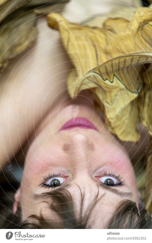 Portrait of a young sexy woman with brown hair artfully covered between leaves of a green and dry, withered decorative banana tree. Girl Dead plant Banana Tree