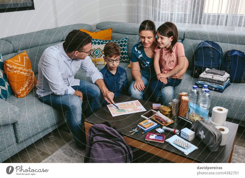 Father explaining to his family the emergency assembly point father map backpack prevention smiling disaster evacuation safety cheerful pointing necessities