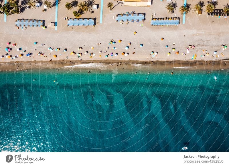 Aerial view of the sea and many people on the beach in Spain holidays costa del sol tree palm tree towel umbrellas leisure relax vacations concept copy space