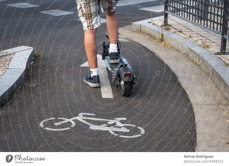 Detail of an electric scooter driven by a man while waiting his turn to cross a road. E-Scooter is allowed in bike lanes. balance battery board caucasian city