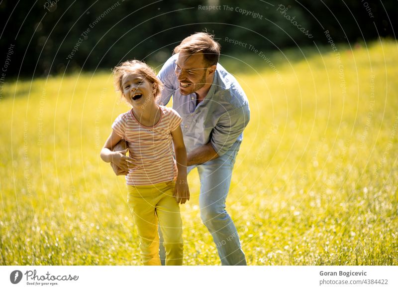 Father with daughter having fun on the grass at the park beautiful beauty caucasian child childhood closeness dad day enjoying expressions exterior family