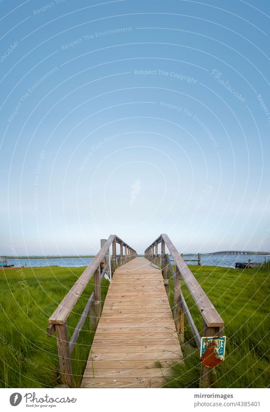 wood platform boardwalk to boat dock and waterfront background beach beautiful blue bridge grass green landscape nature nice daylight outdoor park path