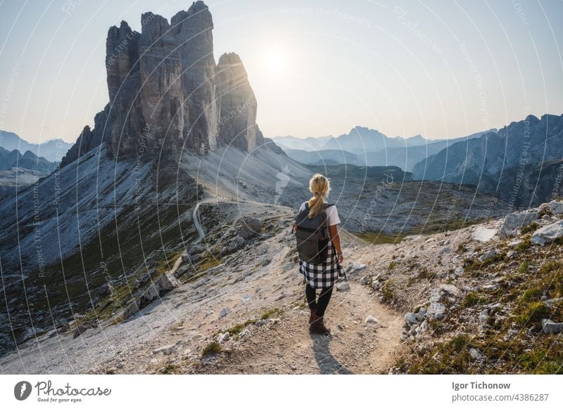 Women hiker with backpack enjoying the Tre Cime di Lavaredo during sunset. Dolomites, Italy lavaredo three peaks mountain landscape woman nature alpine travel