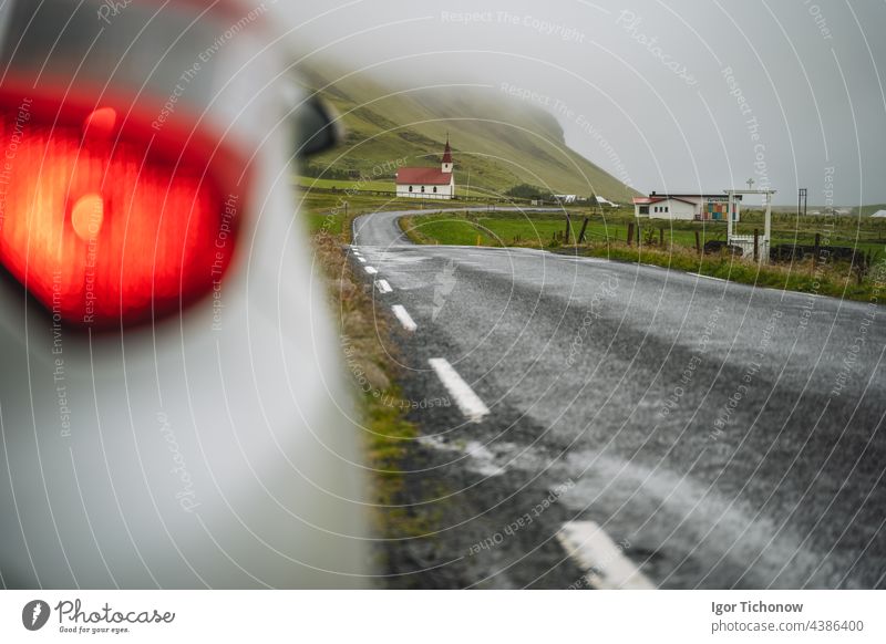 Car stoped on the road with view of typical rural Icelandic Church with red roof in Vik region. Iceland church summer horizontal rent iceland landscape chapel