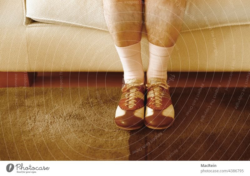 Man sitting on the sofa with golf shoes and white stockings Footwear Golf shoes socks White white socks Sofa sits Sit sedentary seating position well-behaved