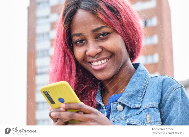 Funky ethnic woman with smartphone on street message style dyed hair color urban informal hipster female young black african american millennial modern