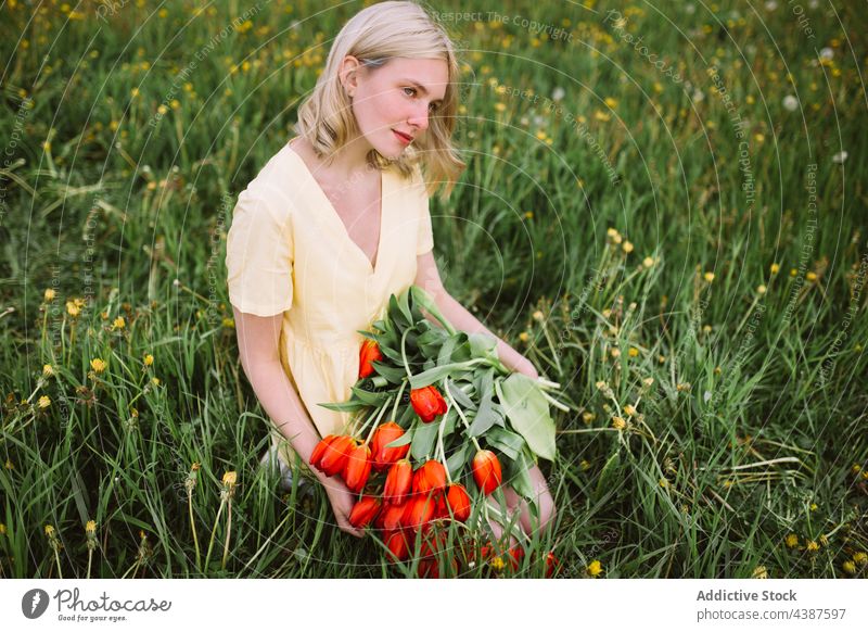 Gentle woman with bouquet of red tulips in field flower summer bunch meadow tender smile female content bloom blossom romantic young nature countryside flora