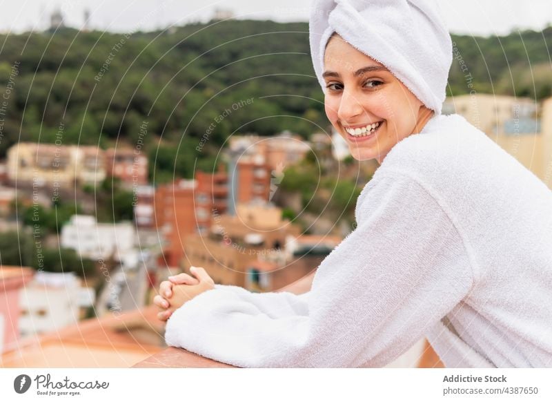 Cheerful female resting on balcony after shower woman skin care routine weekend hygiene smile morning young cheerful procedure spa towel bathrobe relax treat