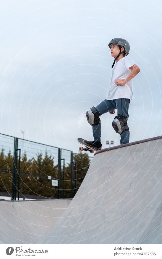 Teen boy riding skateboard in skate park skater ride teenage activity skill energy stand hobby urban move hand on waist action active serious determine summer