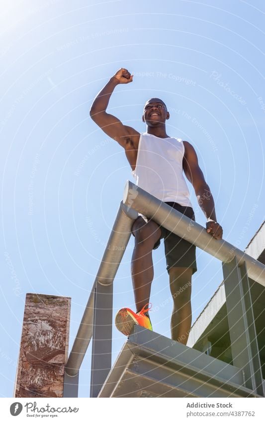 Happy black sportsman celebrating success on terrace in city celebrate victory triumph enjoy goal achieve winner athlete male ethnic african american muscular