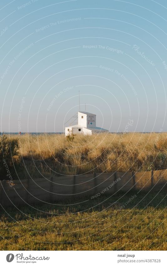 Cubist building of the Life Guards behind dune grass at the sea in front of blue sky. Ocean Horizon Building Container cubistic Architecture Blue sky White