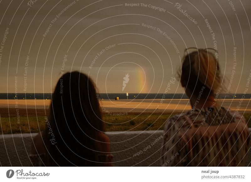 Two silhouettes of women look at a rainbow and hope for better weather vacation Weather Storm Thunder and lightning Rainbow Dark Dramatic Horizon Ocean Beach