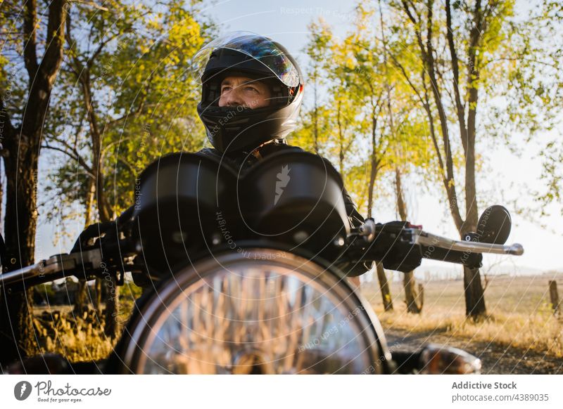 Focused Mature Male Biker Preparing For Riding In Sunny Day motorbike helmet biker man adventure rider travel road action active autumn blur brutal countryside