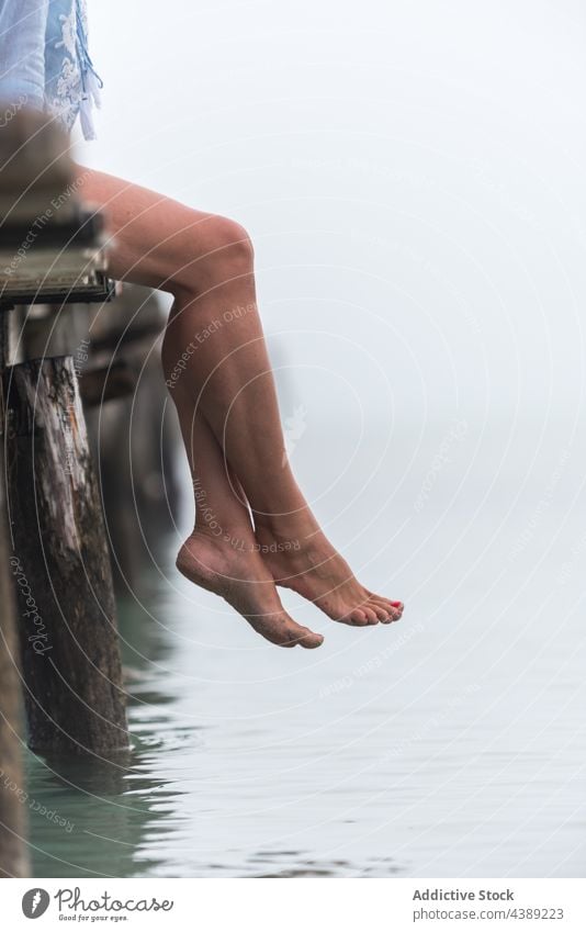 Crop woman sitting on pier in foggy morning sea mist quay wooden calm female playa de muro alcudia mallorca spain nature water peaceful tranquil serene shore