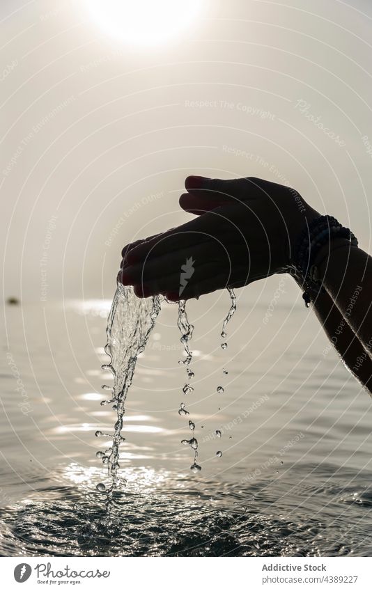 Crop woman with handful of water in sea drop droplet morning wet sunlight fresh female playa de muro alcudia mallorca spain harmony calm tranquil peaceful