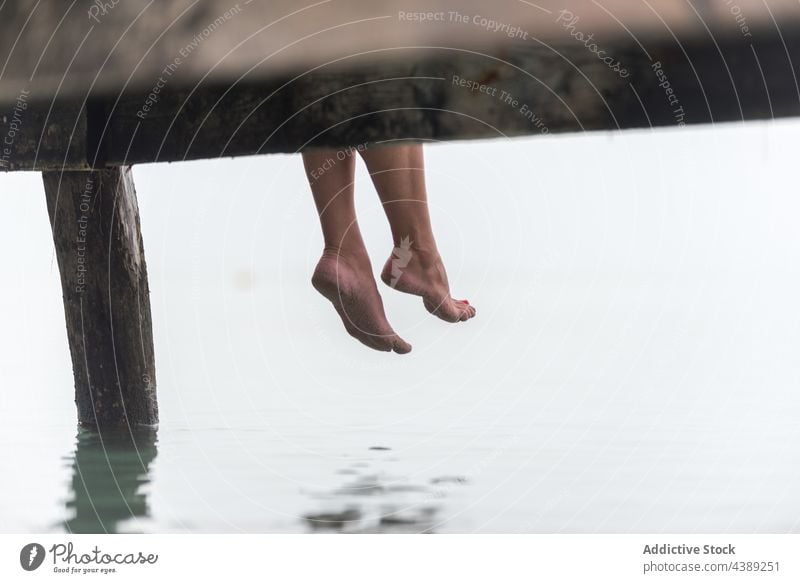 Crop woman sitting on pier in foggy morning sea mist quay wooden calm female playa de muro alcudia mallorca spain nature water peaceful tranquil serene shore