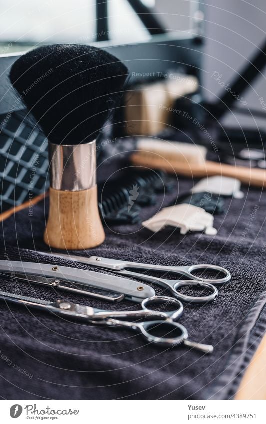 Close-up shaving brush, razor, scissors, combs on the table on a black towel. Professional barber tools and equipment. Barbershop. Professional mens shaving and haircut, hair care. Vertical shot