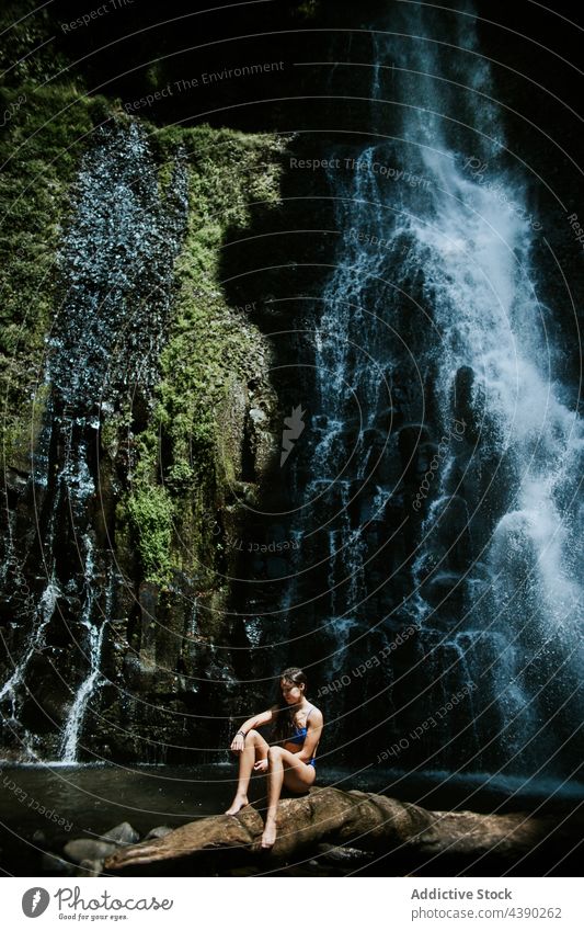 Young woman resting near waterfall rock nature traveler moss relax stone alone fresh splash female tourist vacation journey recreation costa rica los chorros