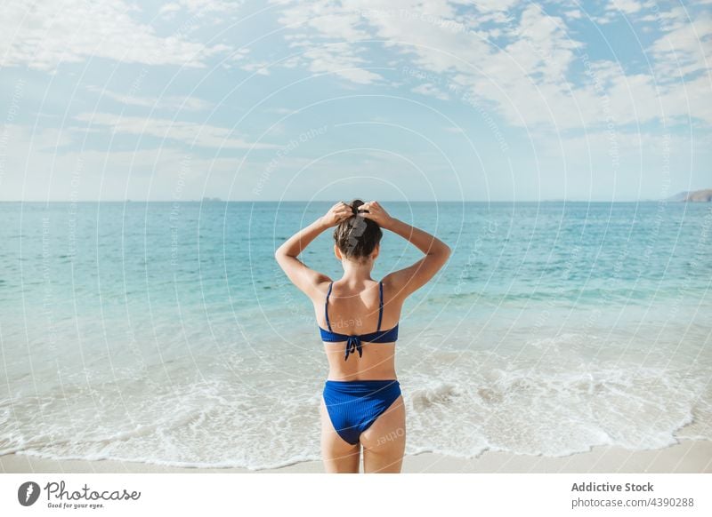 Anonymous woman spending summer day on beach sea ocean bikini sand alone nature travel female vacation coast seashore swimwear long hair brunette beachwear