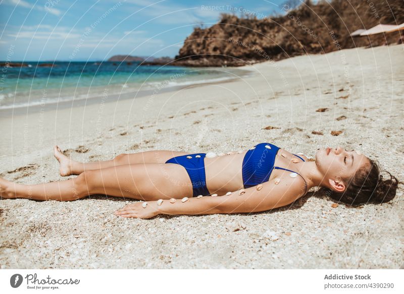 Relaxed woman sunbathing on beach ocean relax seashell sand alone summer travel sunlight nature female vacation coast young seashore holiday bikini seaside