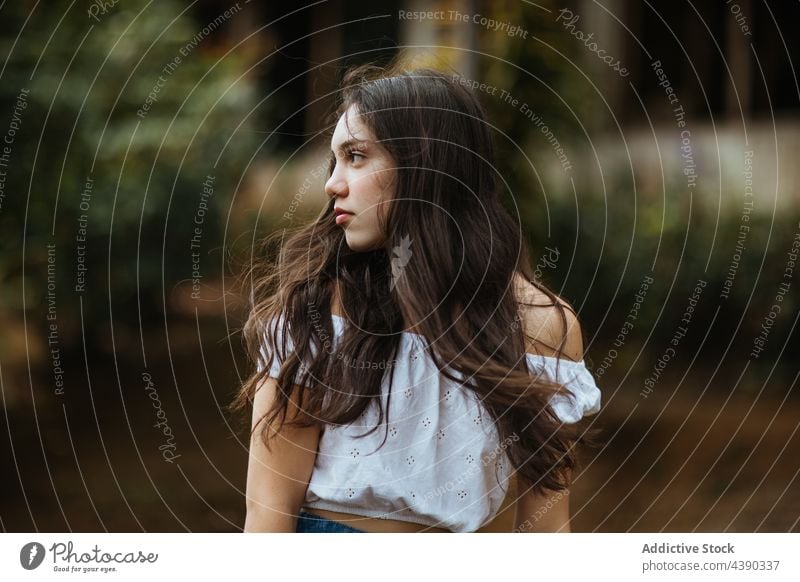 Dreamy young woman in nature dreamy thoughtful summer long hair pensive brunette teenage feminine adolescent female crop top romantic lonely solitude pure