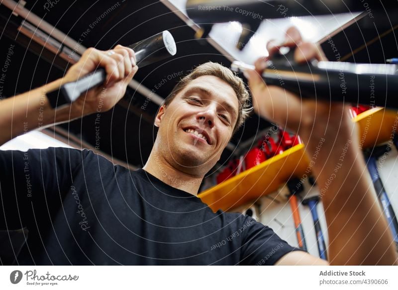 Smiling man repairing bicycle in workshop mechanic fix hammer service bike garage male tool smile cheerful delight content equipment professional job metal